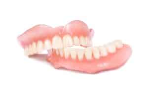 Close-up photo of a realistic upper digital denture in white acrylic material. It has natural-looking pink gum tissue and a full arch of white teeth.