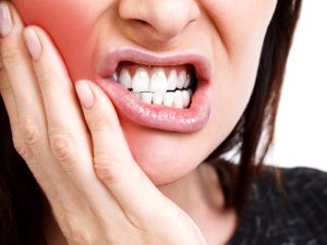 Woman with toothache holding her jaw, worried about dental crown falls off and causing pain.