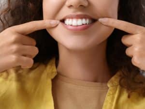 Woman smiling, highlighting teeth enhanced with veneer materials for aesthetic improvement.