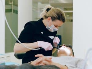 Dentist examining patient’s teeth to address persistent tooth sensitivity and pain in a dental clinic setting.