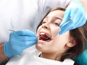 Child receiving a dental fissure sealant treatment at the dentist for cavity protection.