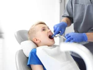 A child receiving a check-up after an infected molar extraction, with the dentist monitoring the healing process.