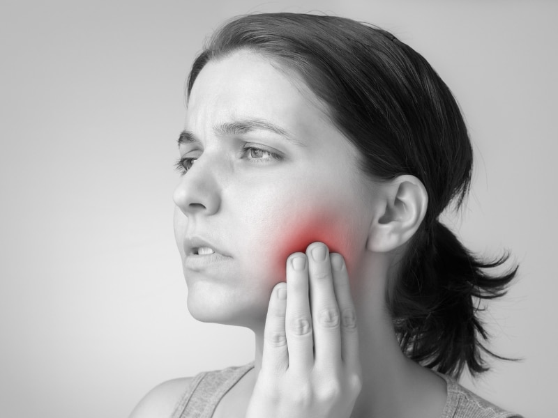 Woman with tooth pain caused by neglecting her dental schedule and delaying care.