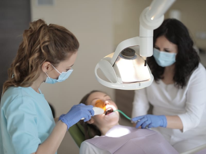 Two dental professionals providing treatment as part of patient’s dental schedule in a clinical setting.